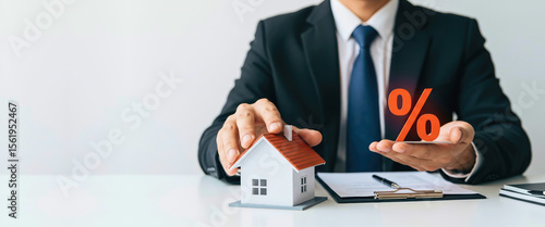 Businessman presenting house model and percentage sign in office  