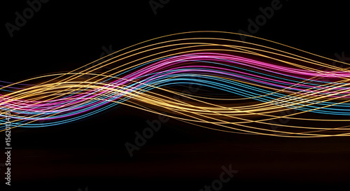 Abstract waves of colorful light trails on a dark background, dynamic motion and energy. AI
