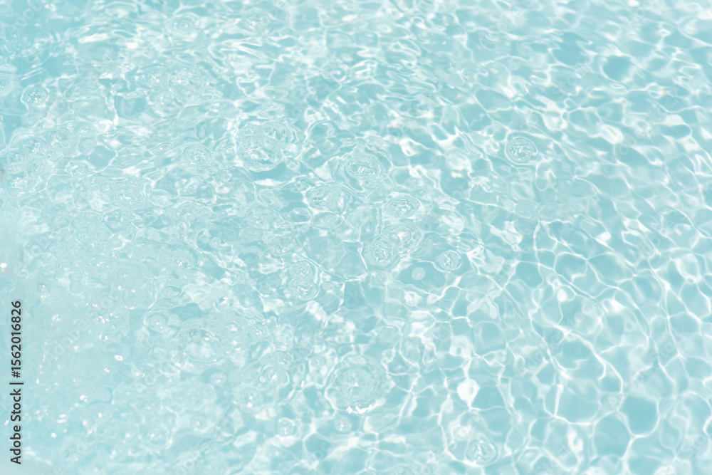 Obraz premium Blue water with ripples on the surface. Defocus blurred transparent blue colored clear calm water surface texture with splashes and bubbles. Water waves with shining pattern texture background.