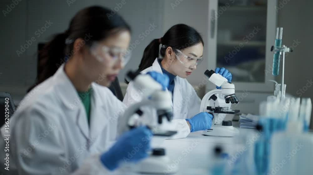 Female scientists using microscopes and performing scientific experiment in a modern laboratory