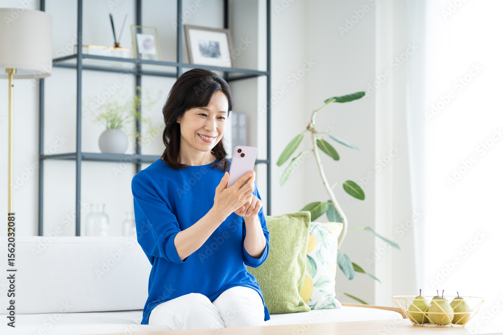 リビングでスマホを使うミドルの主婦 リビングでスマホを使うミドルの主婦