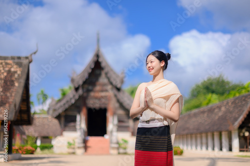Foto charming Thai woman in traditional Lanna attire respectful wai at Wat Ton Kwen, Chiang Mai during summer