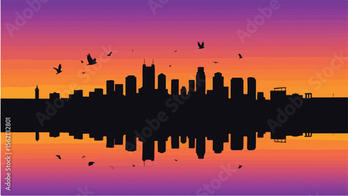 Silhouetted city skyline reflected in water with birds flying across a vibrant sunset sky