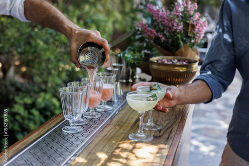 Outdoor cocktail preparation with fresh ingredients and elegant glassware