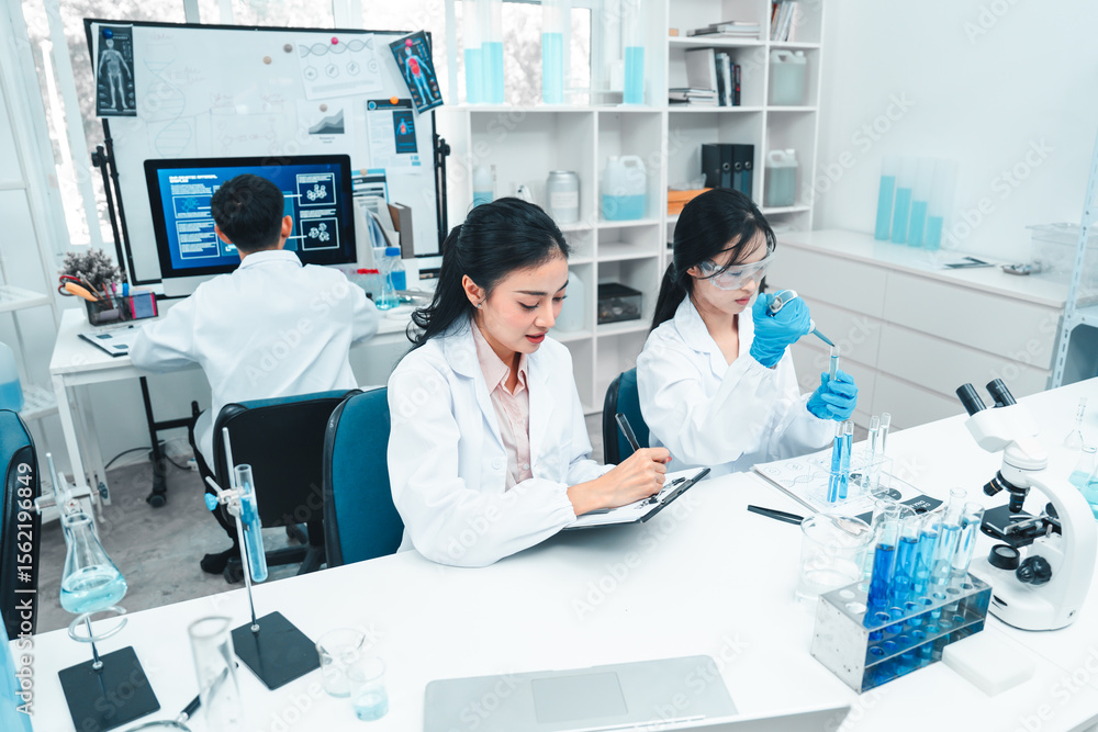 Fototapeta premium Two female scientists analyzing test tube samples in a laboratory setting. One supervises while the other conducts an experiment. Concept of science education, teamwork, and research collaboration.