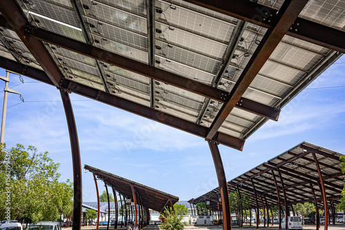 Solar panel arrays installed on metal structures above a parking lot, providing shade while generating renewable energy.