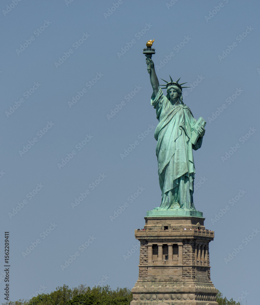 Obraz premium state isolated against a pale blue sky (iconic icon of freedom prosperity immigration arrivals) lady with torch and crown new york city harbor usa america of french gift new jersey