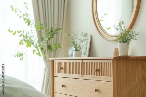 Modern solid wood cabinet with drawers and slat design, natural color Japanese minimalist bedroom interior with round wall mirror and green plants