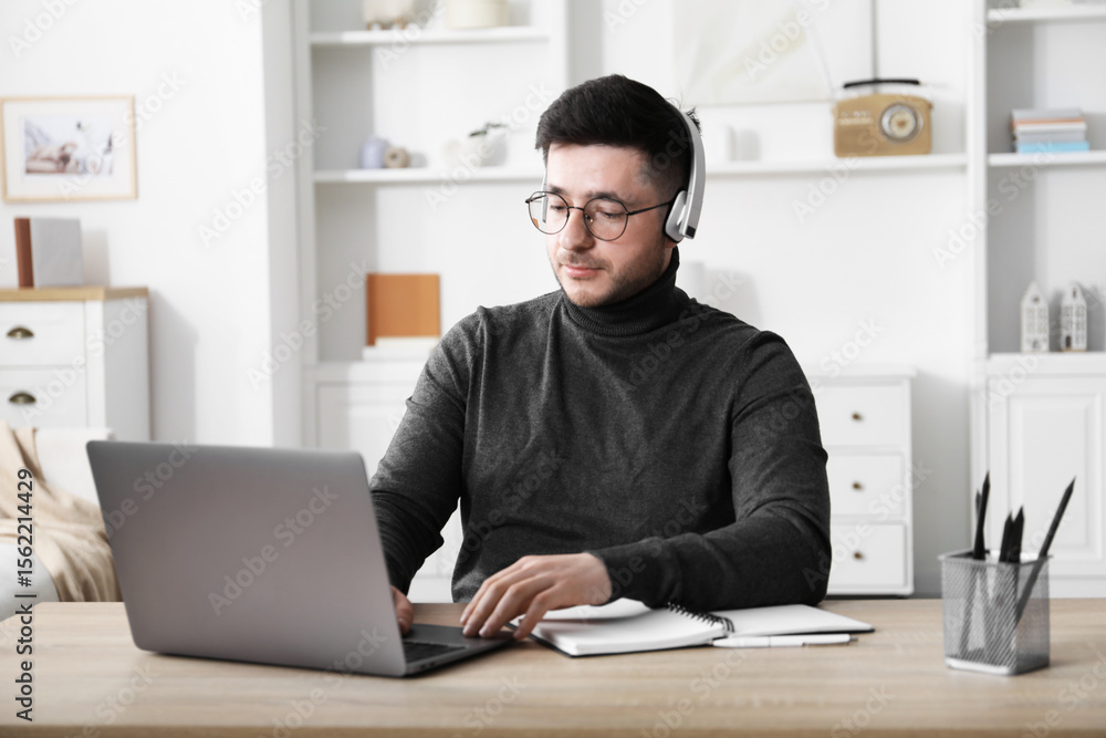 Fototapeta premium Man learning online using laptop at desk indoors. Self-study
