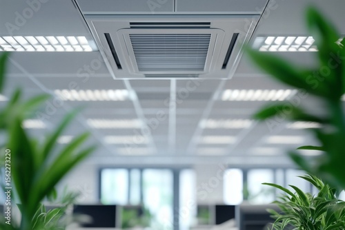 Office ceiling with a central ventilation system and fluorescent lighting, blurred green plants in foreground, serene work environment.