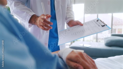 Asian woman patient describes her symptoms to an oncologist while sitting on a bed and looking at a man doctor in a lab coat in a hospital ward, health and medical care concept