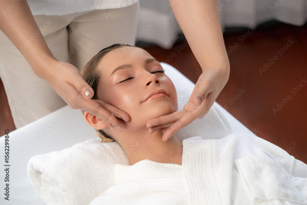 Caucasian woman enjoying relaxing anti-stress head massage and pampering facial beauty skin recreation leisure in dayspa modern light ambient at luxury resort or hotel spa salon. Quiescent Caucasian woman enjoying relaxing anti-stress head massage and pampering facial beauty skin recreation leisure in dayspa modern light ambient at luxury resort or hotel spa salon. Quiescent