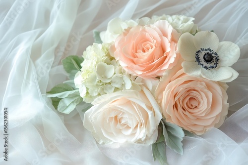 Delicate bouquet of pastel roses and anemones on sheer fabric.