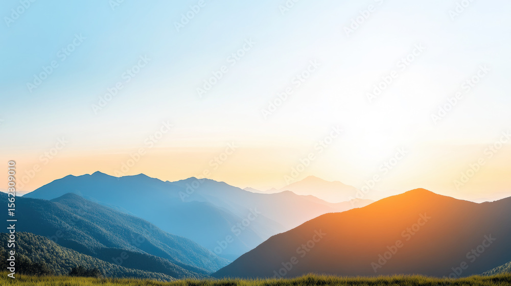 Fototapeta premium Serene landscape of rolling hills and soft mountains glowing under golden twilight, with clear blue sky and vibrant sunlight creating peaceful atmosphere