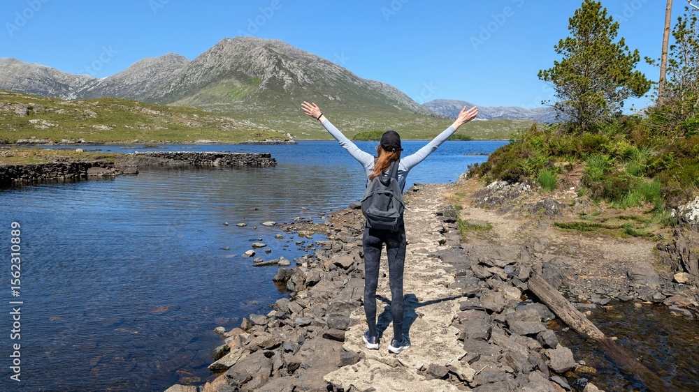 Obraz premium Hiker girl with hands up at twele pines island, Connemara, Galway, Ireland, backpacker adventure and lifestyle, nature and mountains background