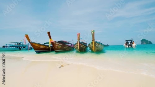 Longtail boats rest on a sandy beach with turquoise water in thailand