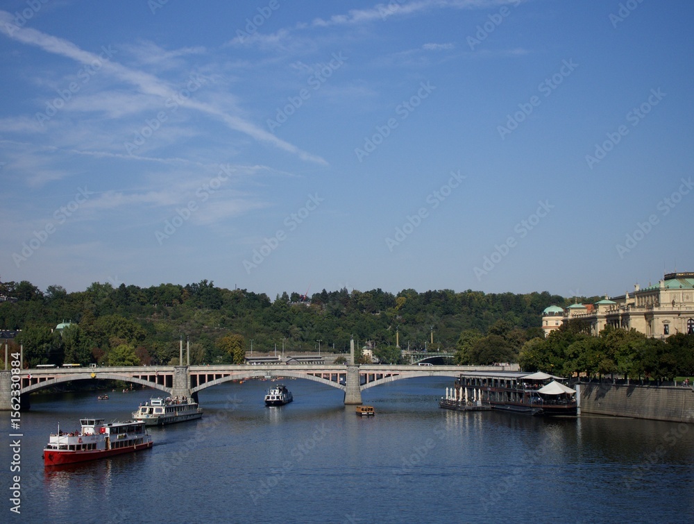Obraz premium A picturesque river scene with bridges, boats, and a lush green bank.