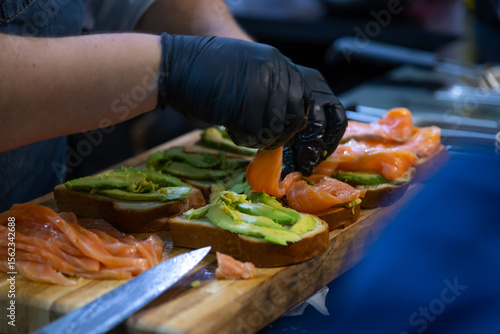 Preparing gourmet salmon avocado toast in a professional kitchen setting