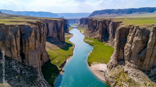 A river flows through a canyon with green grass on the banks