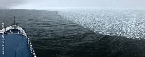 A ship's bow glides along the edge of the arctic ice sheet