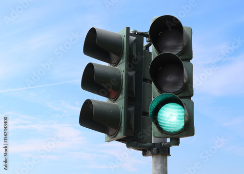 Green traffic light with the sky as background.