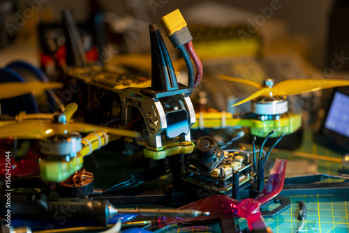 Yellow propeller 5-inch FPV drone with visible circuit components on cluttered workspace table