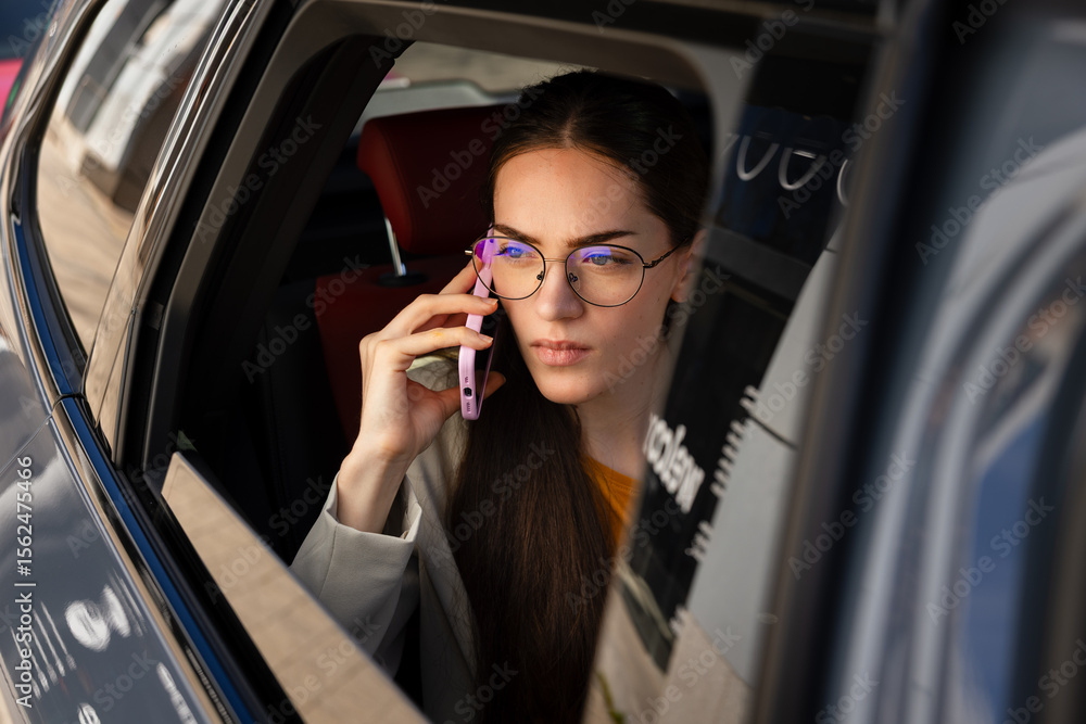 Woman in car talking on phone looking out window Woman in car talking on phone looking out window