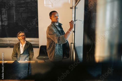 Male entrepreneur writing ideas on screen in meeting at office