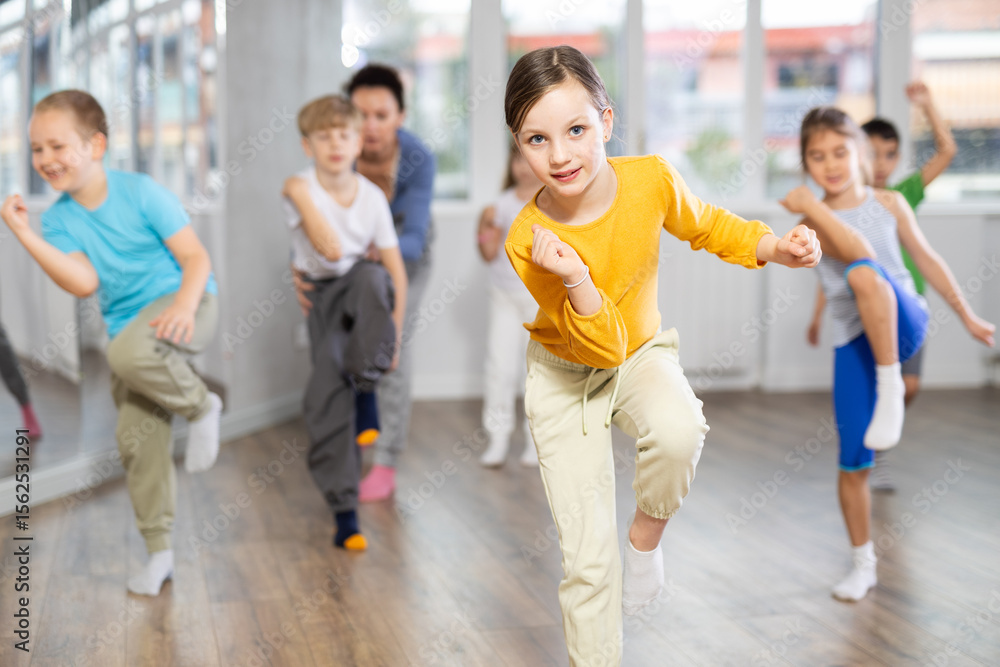 Obraz premium Children studying modern style dances with female teacher in dance class indoors