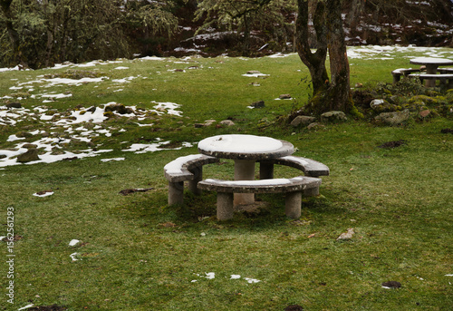 Snow covered stone picnic table, first snowfall of the season in the mountains
