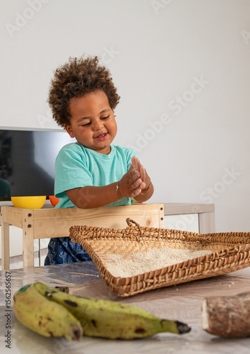 Curious african child playing with rice in a tipical congolese basket