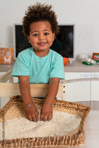Curious african child playing with rice in a tipical congolese basket