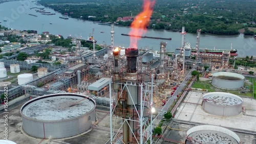 An aerial view of an oil refinery plant at dusk with flames