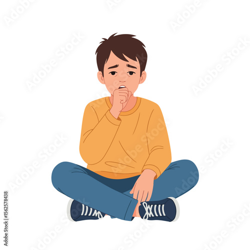 A young boy sits cross-legged, coughing into his hand, looking unwell.