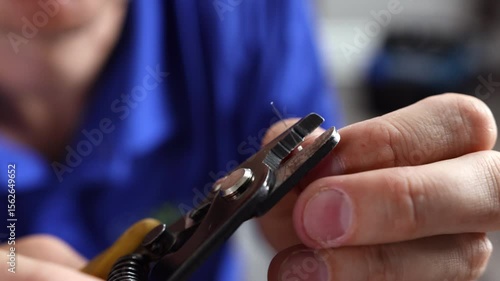 A fiber technician strips and cleaves an optical fiber cable using a precision stripping tool, second short version