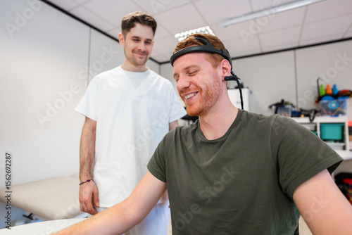 Doctor assisting smiling patient wearing brainwave scanning headset