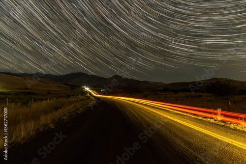 A captivating long exposure image of a car driving down a road at night, with streaks of light trailing behind it, creating a sense of motion and speed.