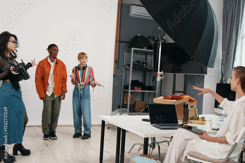 Fotografi Young adult woman directing colleagues and coworkers in a modern workplace, socializing and collaborating on a business project with Gen Z professionals