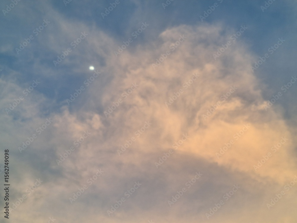 Obraz premium Soft Evening Clouds and a Gentle Moon Glow in the Tranquil Sky at Sunset's Golden Hour
