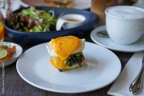 Εκτύπωση καμβά Delicious oozing eggs florentine on white plate with a cup of hot cappuccino, sa
