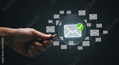 A hand holds a magnifying glass over a verified email icon