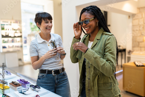 Woman trying new eyeglasses laughing with optician in eyewear store