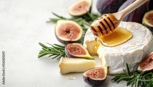 Creamy brie, figs, and honey on a light surface.  Fresh rosemary sprigs enhance the display.  A wooden spoon drizzles honey over the cheese