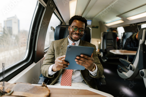 Black Businessman Using Digital Tablet While Traveling on Modern Train