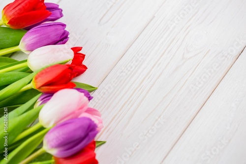 Fototapeta Naklejka Na Ścianę i Meble -  Colorful tulip blossoms with green stems are lining diagonal white wood planks in flat design