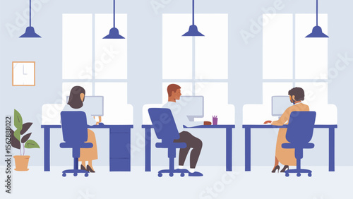 People are sitting at their desks in an office with computers and hanging lights in the room area