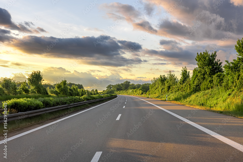 Naklejka premium Empty highway in greenery. Forest road. Sunset light