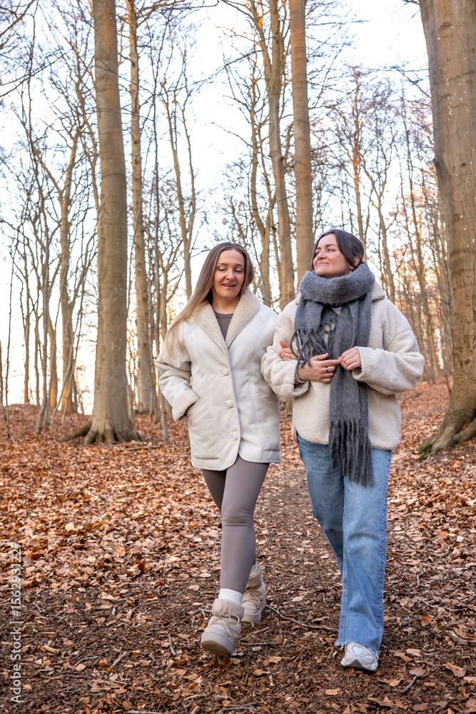 Fototapeta premium Two female friends on a walk in the forest. Friends walking through the forest. People in nature.