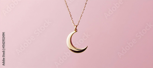 Crescent moon pendant on a gold chain necklace displayed on soft pink background featuring minimalist jewelry style with simple celestial design in close-up studio shot

