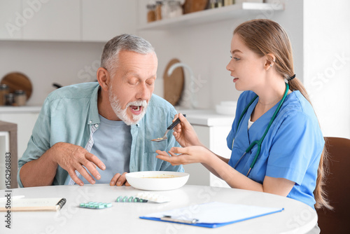 Nurse feeding senior man su...